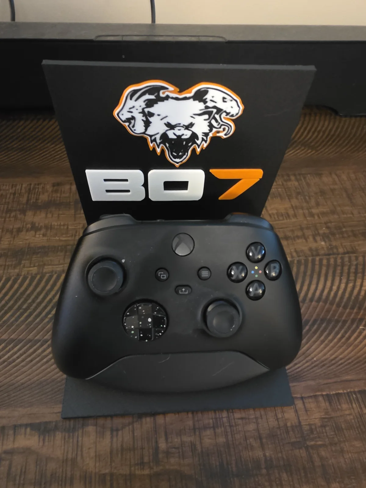 Game controller displayed on a black custom BO7 stand