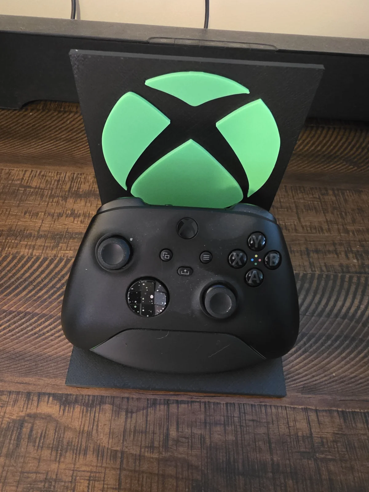Xbox controller displayed on a black stand with a green emblem